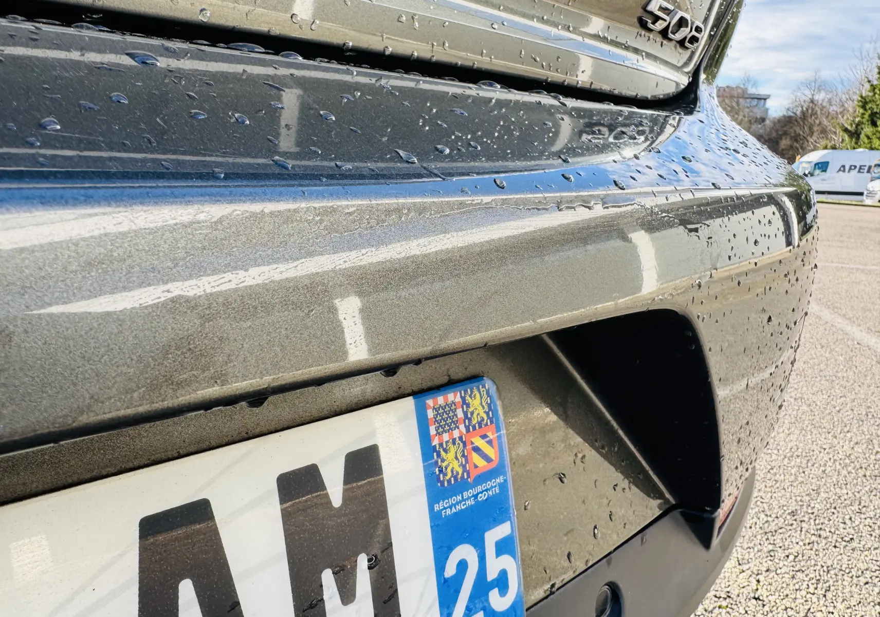 Gros plan sur l’arrière droit gris amazonite d’une Peugeot 508 2019 avec logo et plaque d’immatriculation humide.