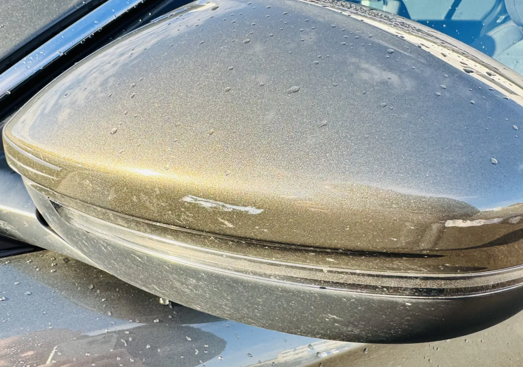 Gros plan sur le rétroviseur droit gris amazonite métallisé du Peugeot 508, avec traces d'eau et rayures visibles.