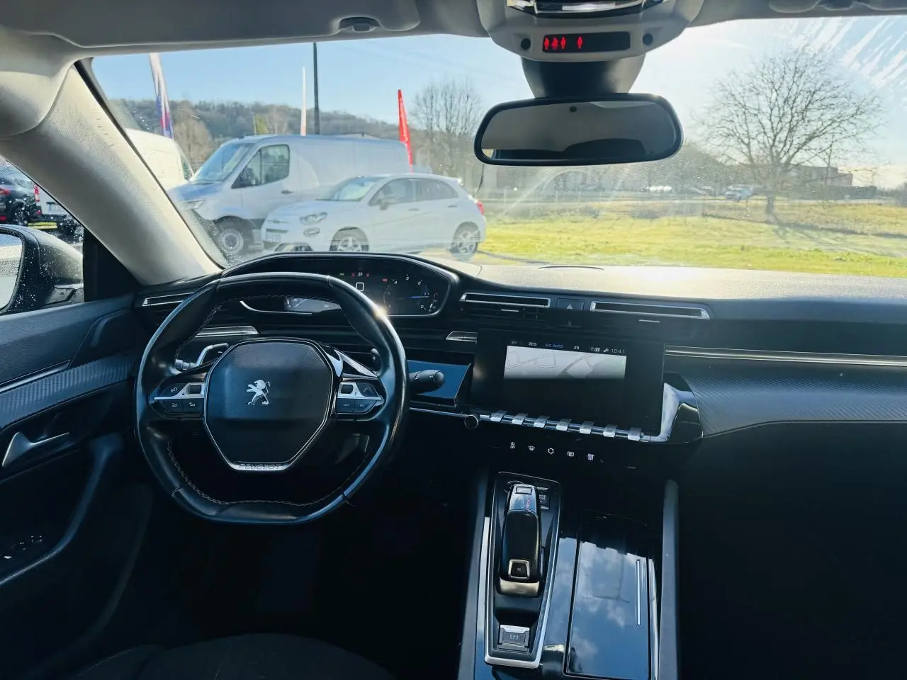 Vue intérieure avant de la Peugeot 508 gris amazonite, volant compact, écran tactile et planche de bord carbone.