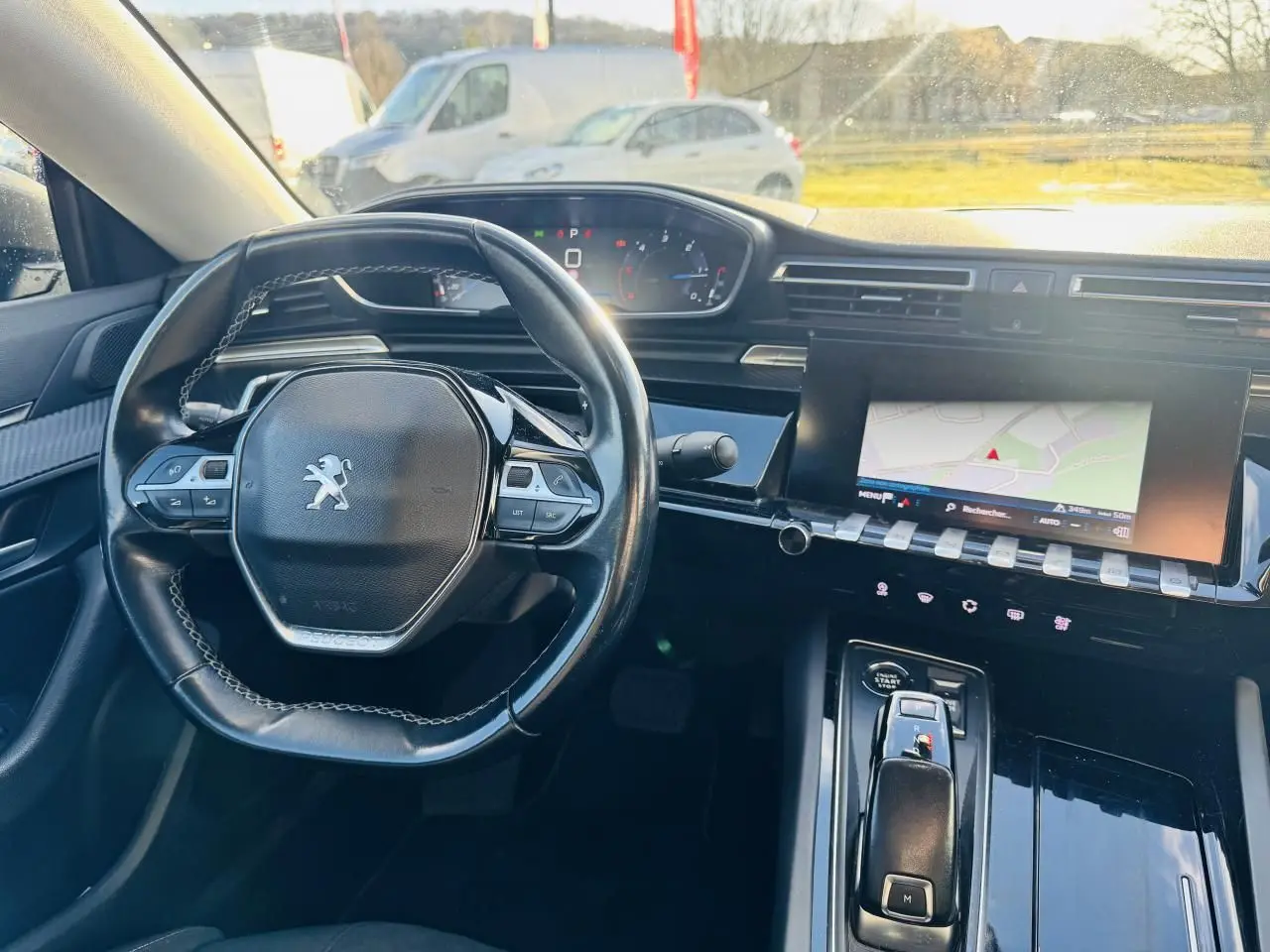 Vue intérieure avant de la Peugeot 508 gris amazonite, volant compact cuir et écran tactile avec navigation allumé.