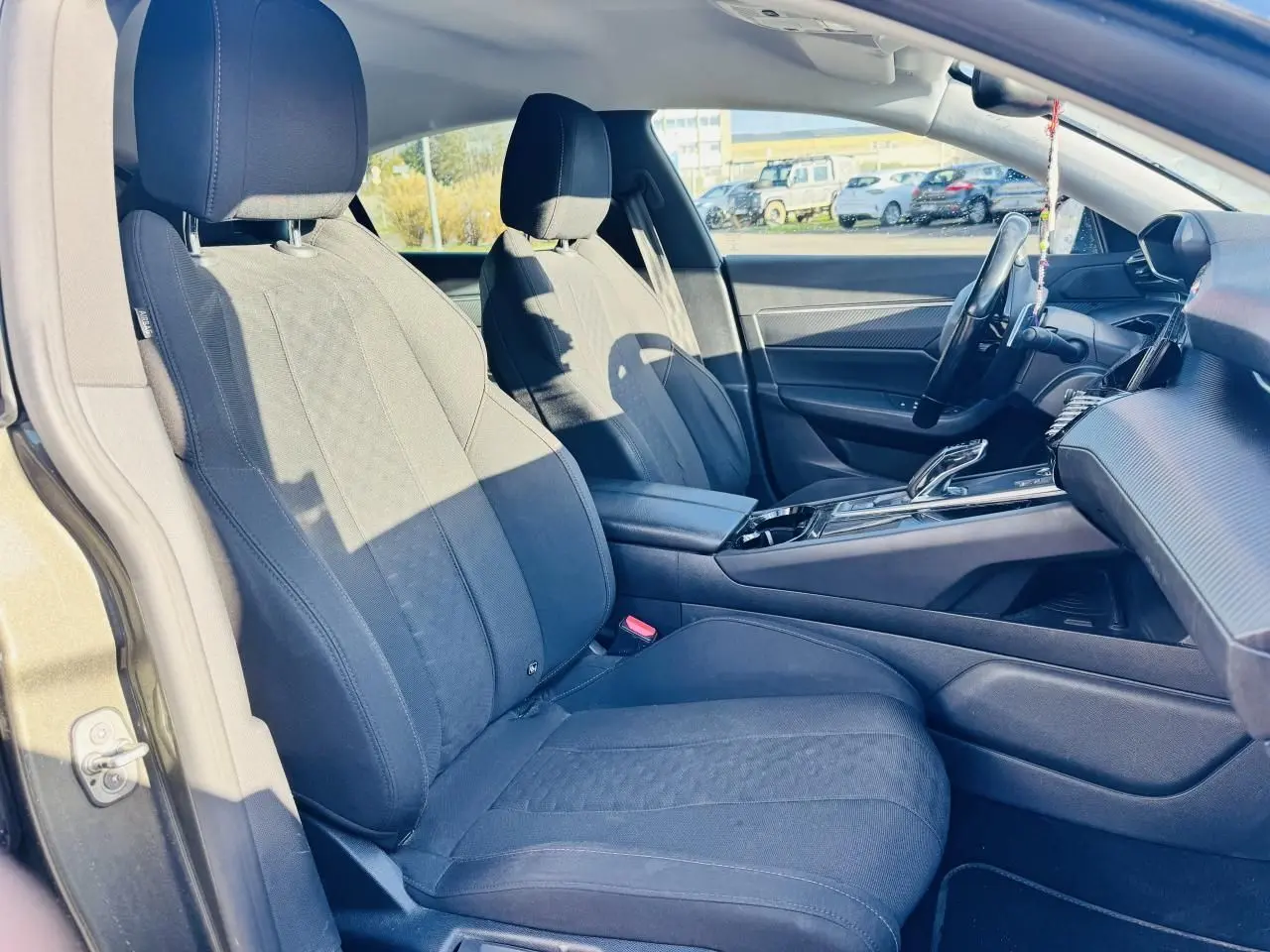 Intérieur de la Peugeot 508 gris amazonite, vue côté gauche sur sièges tissu noir et console centrale moderne.