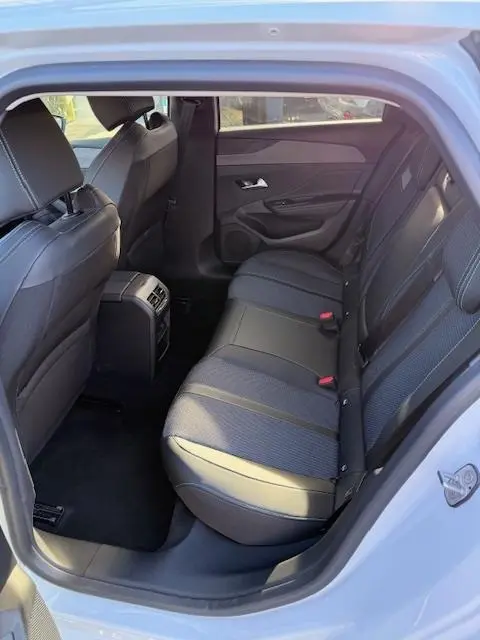 Vue intérieure côté arrière droit de la banquette arrière en tissu et cuir dans une Peugeot 308 Hybrid 145 e-DCS6 Allure blanche.