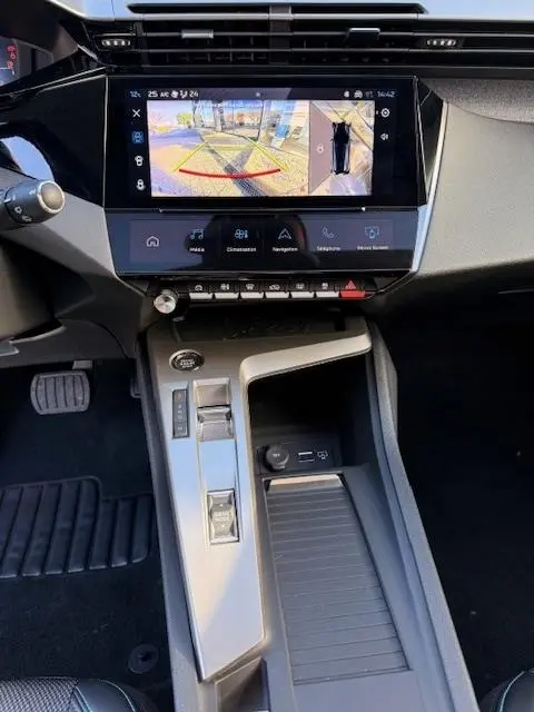 Vue intérieure du tableau de bord et console centrale de la Peugeot 308 Hybrid blanche, écran tactile avec caméra de recul affichée.