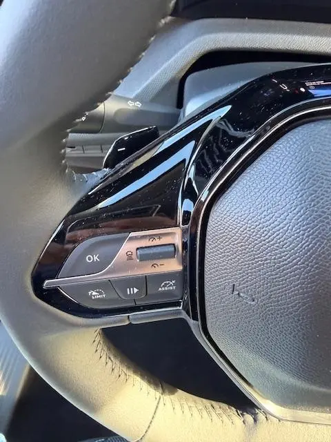 Gros plan sur les commandes multifonctions côté gauche du volant cuir de la Peugeot 308 Hybrid 145 e-DCS6 Allure 2025.