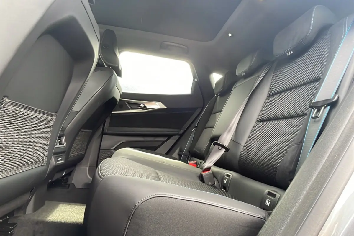 Vue intérieure côté droit sur la banquette arrière en semi-alcantara noir avec surpiqûres bleues et toit panoramique lumineux.
