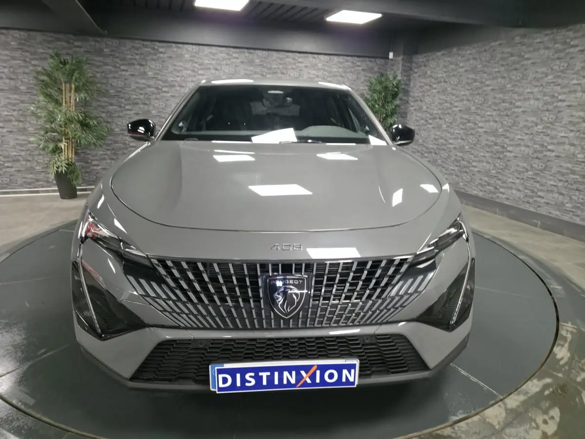 Vue avant d'une Peugeot 408 gris Selenium avec calandre verticale et badge lion distinctif.