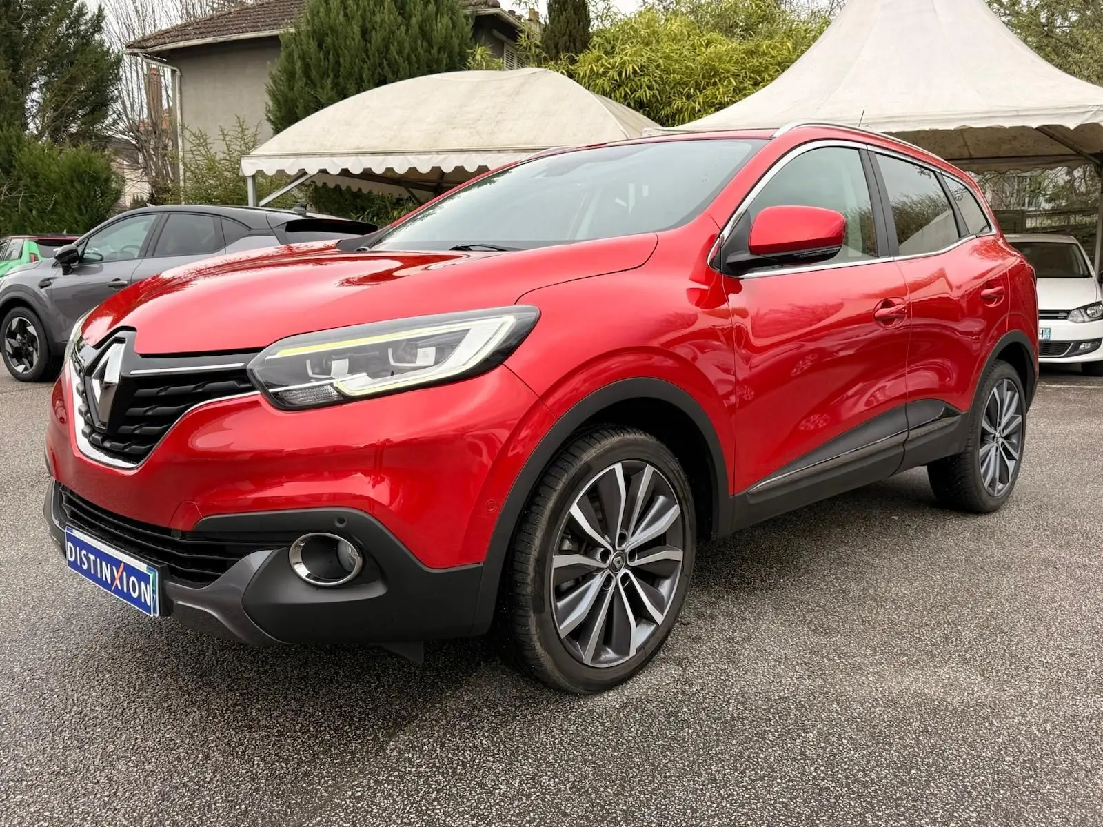 Vue 3/4 avant droite d'un Renault Kadjar rouge flamme avec jantes alliage bicolores et calandre noire brillante.