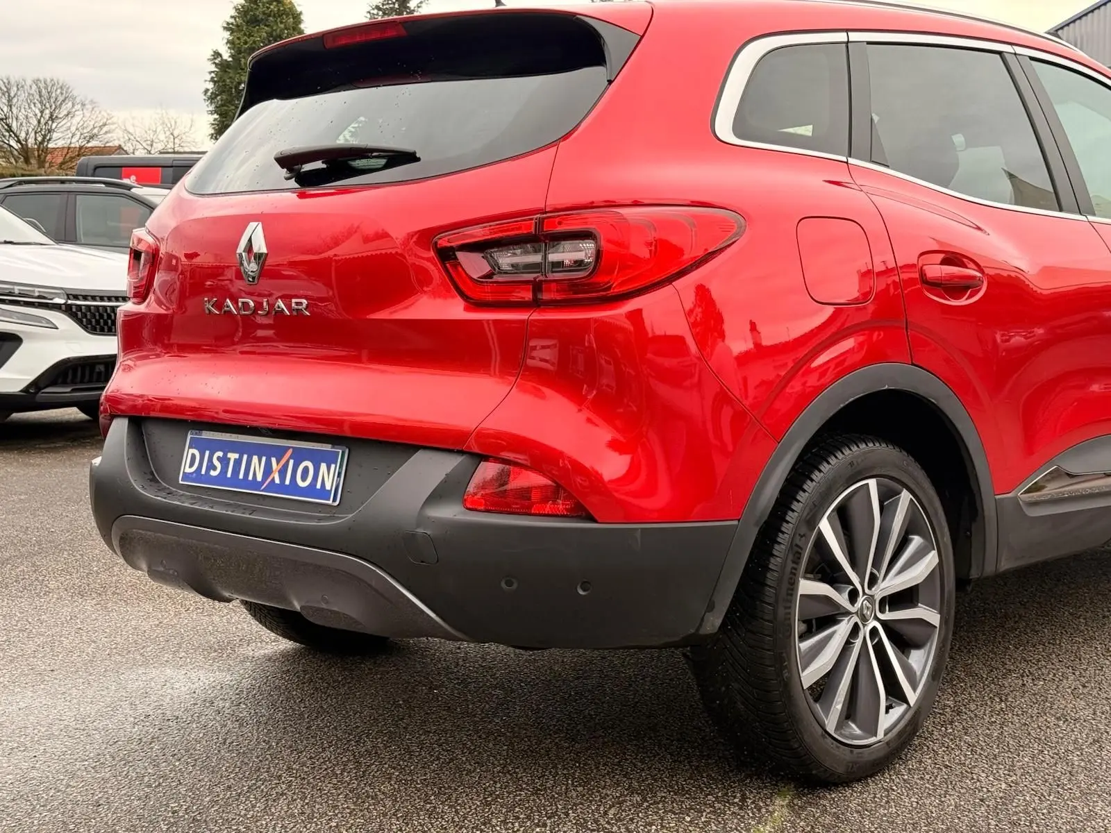 Vue 3/4 arrière droite d'un Renault Kadjar rouge flamme avec jantes alliage bi-ton et détails noirs au pare-chocs.