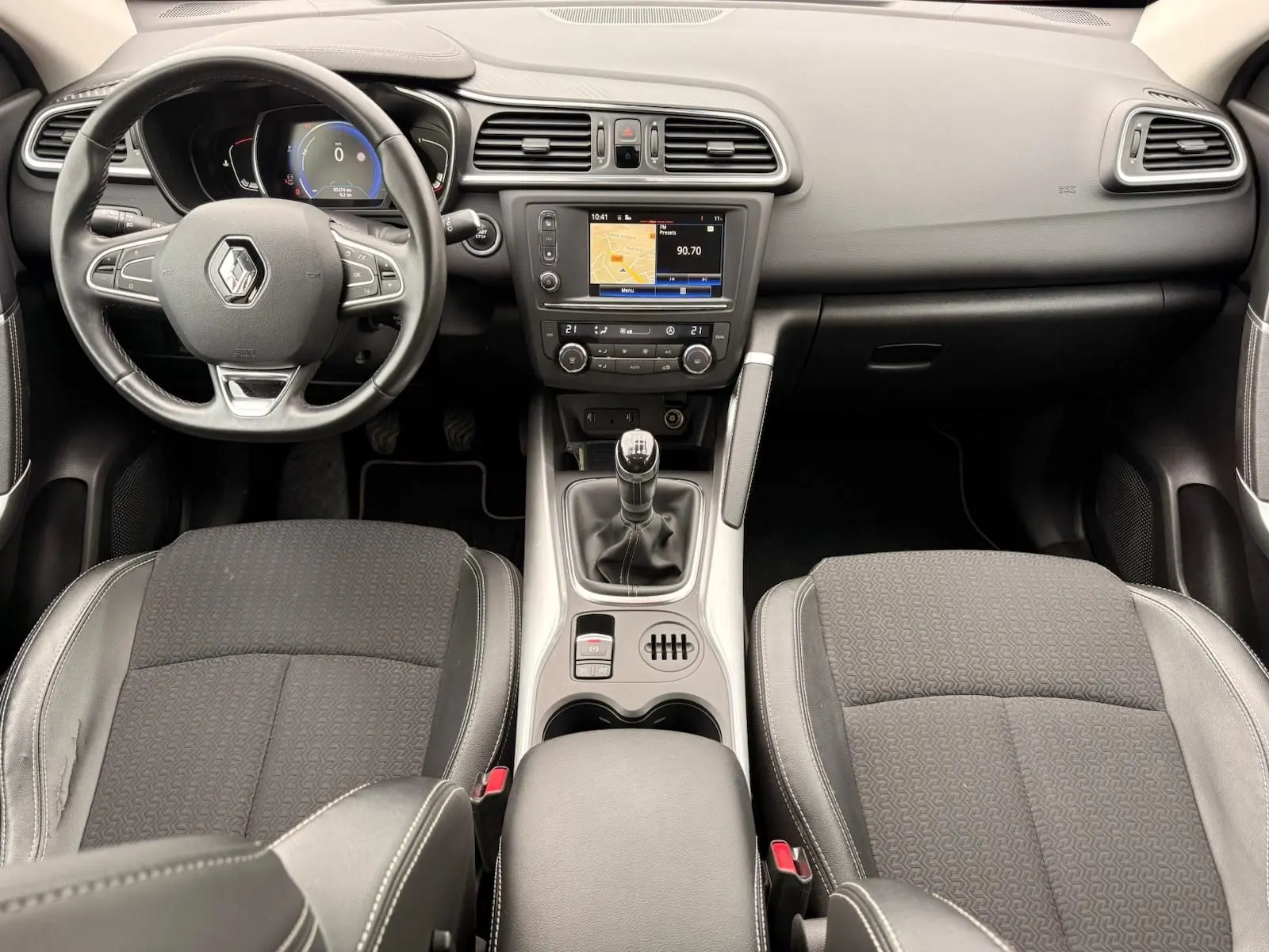 Vue intérieure avant du Renault Kadjar 2016, tableau de bord et volant en cuir noir avec console centrale et boîte manuelle.