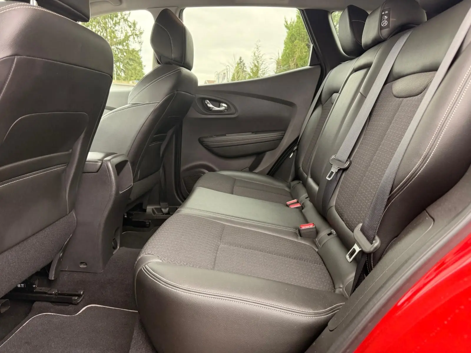 Vue intérieure côté droit des sièges arrière en cuir noir du Renault Kadjar rouge flamme, avec ceinture de sécurité visible.