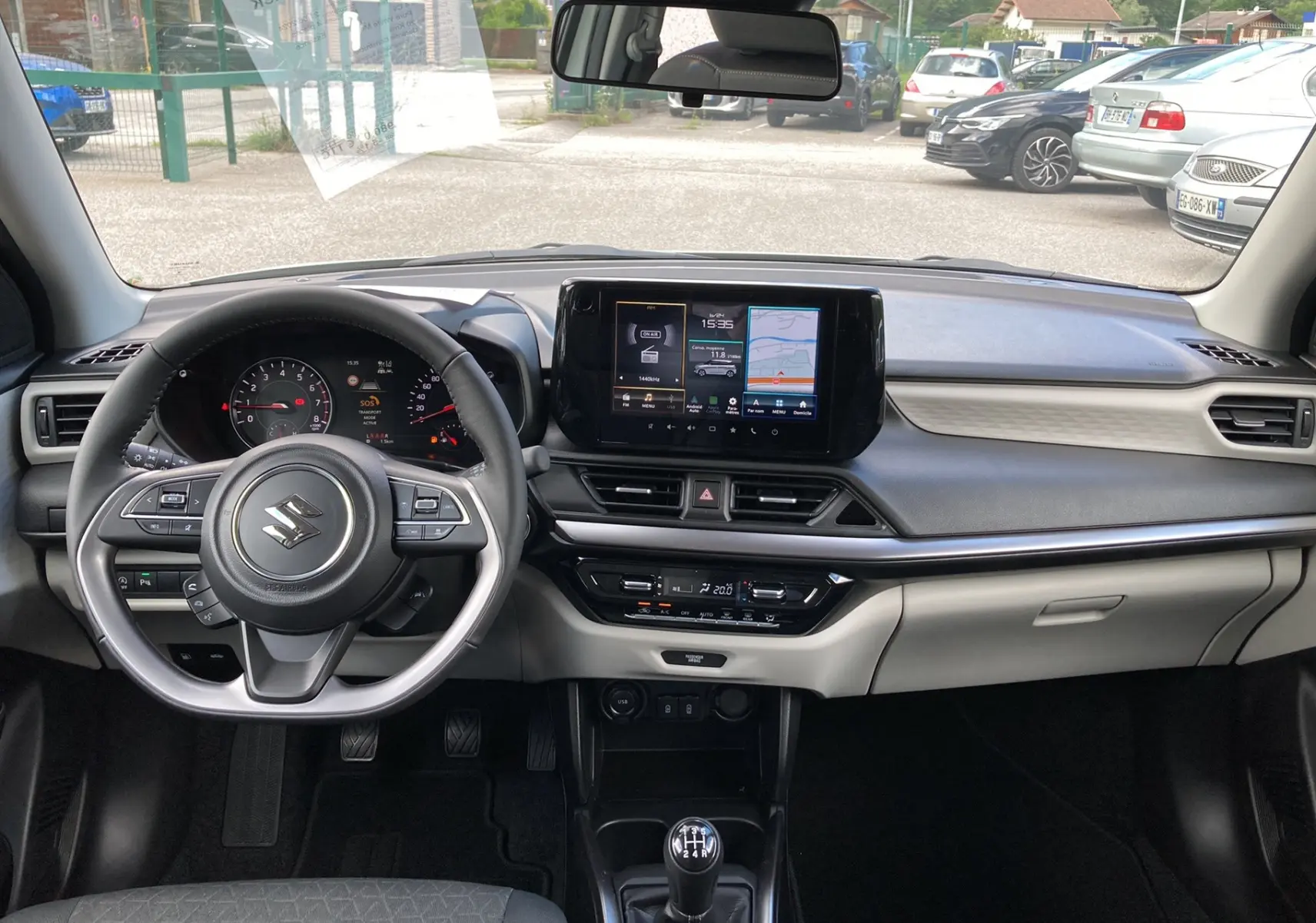 Vue intérieure frontale du tableau de bord et volant cuir multifonctions de la Suzuki Swift 2025 en version hybride.