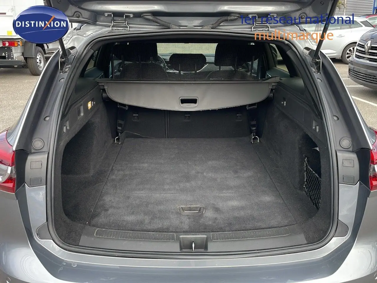 Coffre ouvert vu de l'arrière d'une Opel Insignia Sports Tourer gris acier satiné, montrant l'espace de chargement vide.