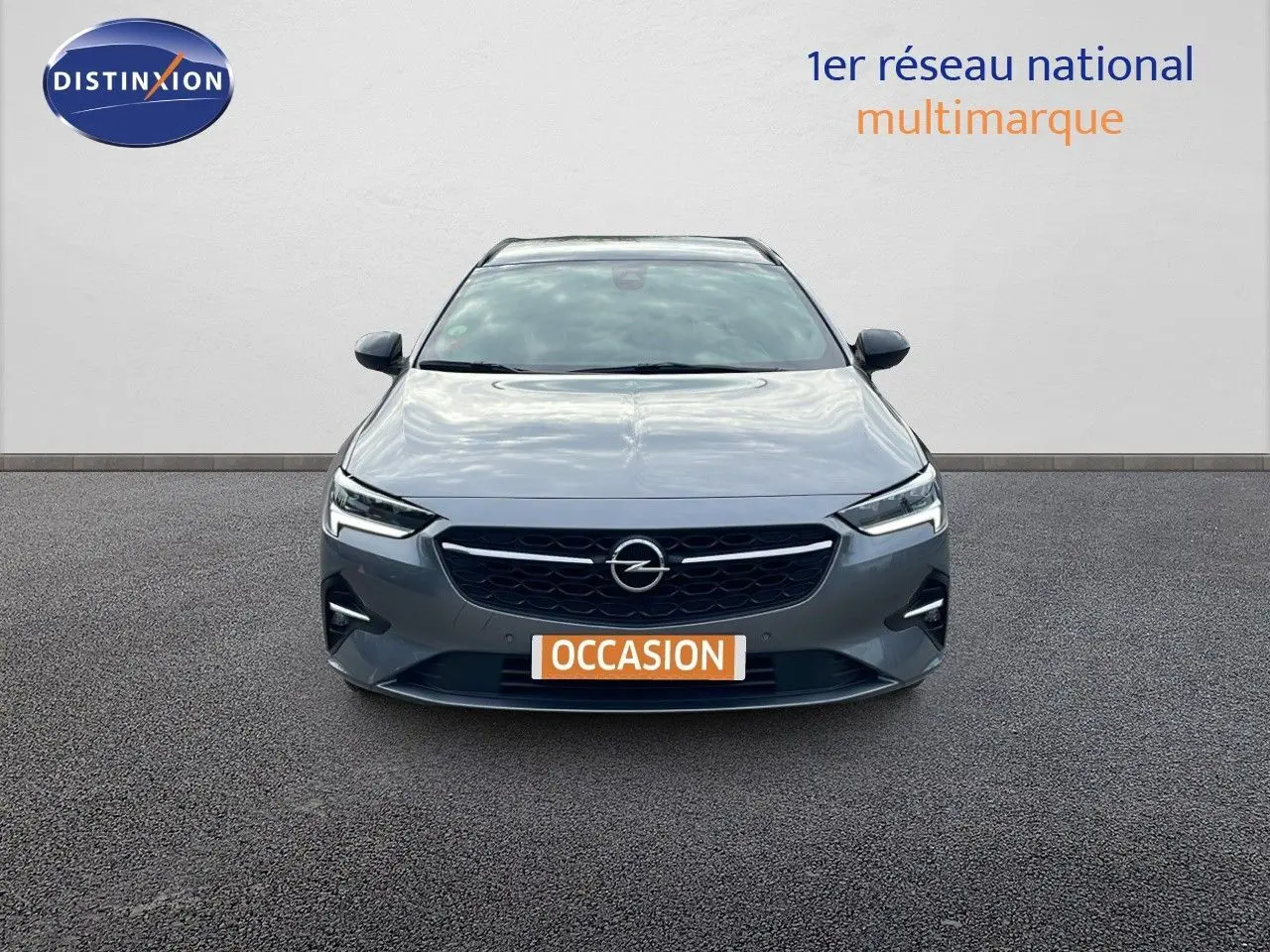 Vue frontale d'une Opel Insignia Sports Tourer gris acier satiné avec calandre noire et phares LED allumés.