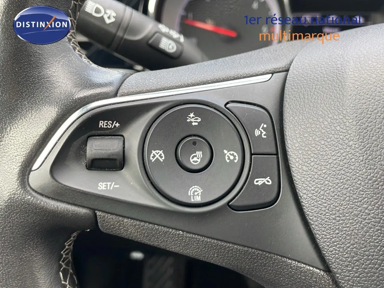 Gros plan sur les commandes au volant noir de l'Opel Insignia Sports Tourer, mettant en valeur les boutons de régulateur et assistance.