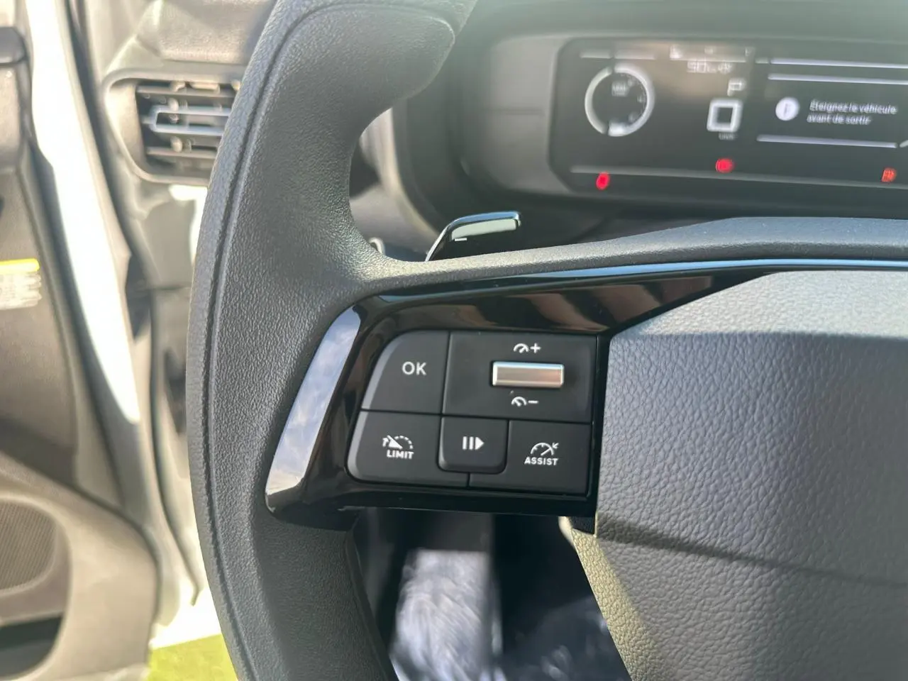 Vue intérieure côté passager du tableau de bord noir du Citroën Berlingo III Van blanc Icy, avec aérateur et commande de lève-vitre.