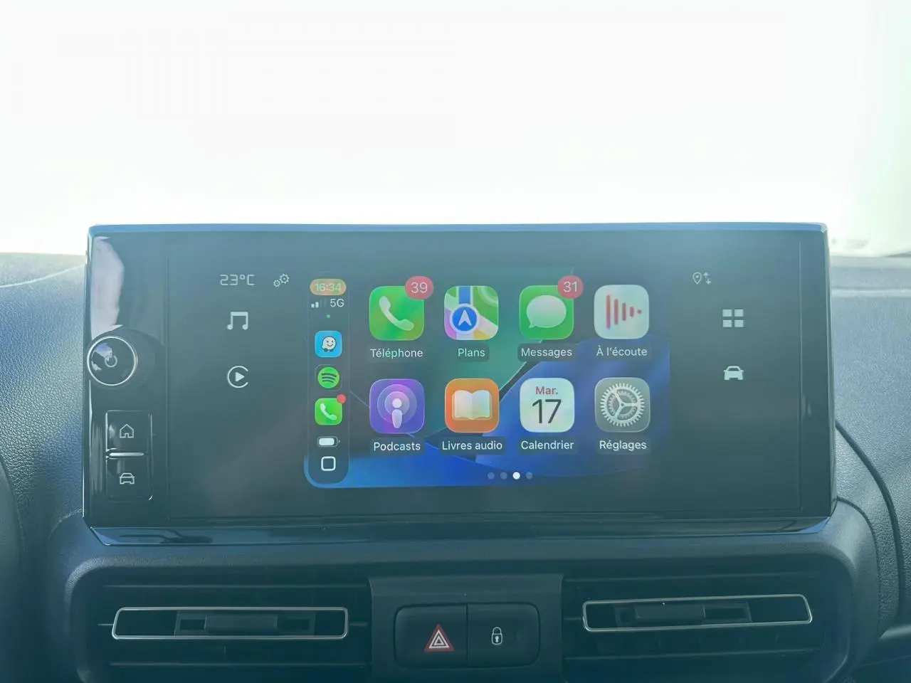 Vue intérieure en gros plan du plafonnier gris clair avec commandes et miroir de courtoisie du Citroën Berlingo blanc.