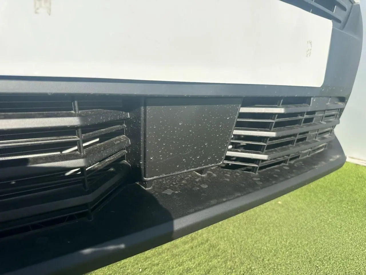 Gros plan sur la calandre noire et la partie basse blanche du Citroën Berlingo III van blanc Icy, vue avant rapprochée.