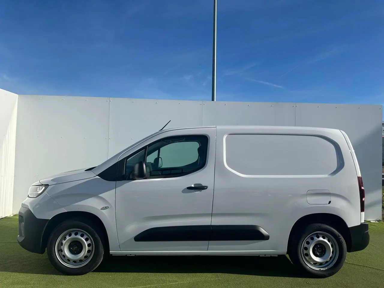 Vue de profil côté gauche d’un utilitaire Citroën Berlingo III blanc Icy avec jantes tôles grises et porte latérale coulissante.