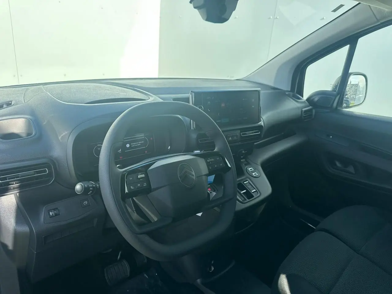 Vue intérieure côté conducteur du Citroën Berlingo blanc Icy, volant multifonctions et écran tactile 10 pouces visible.