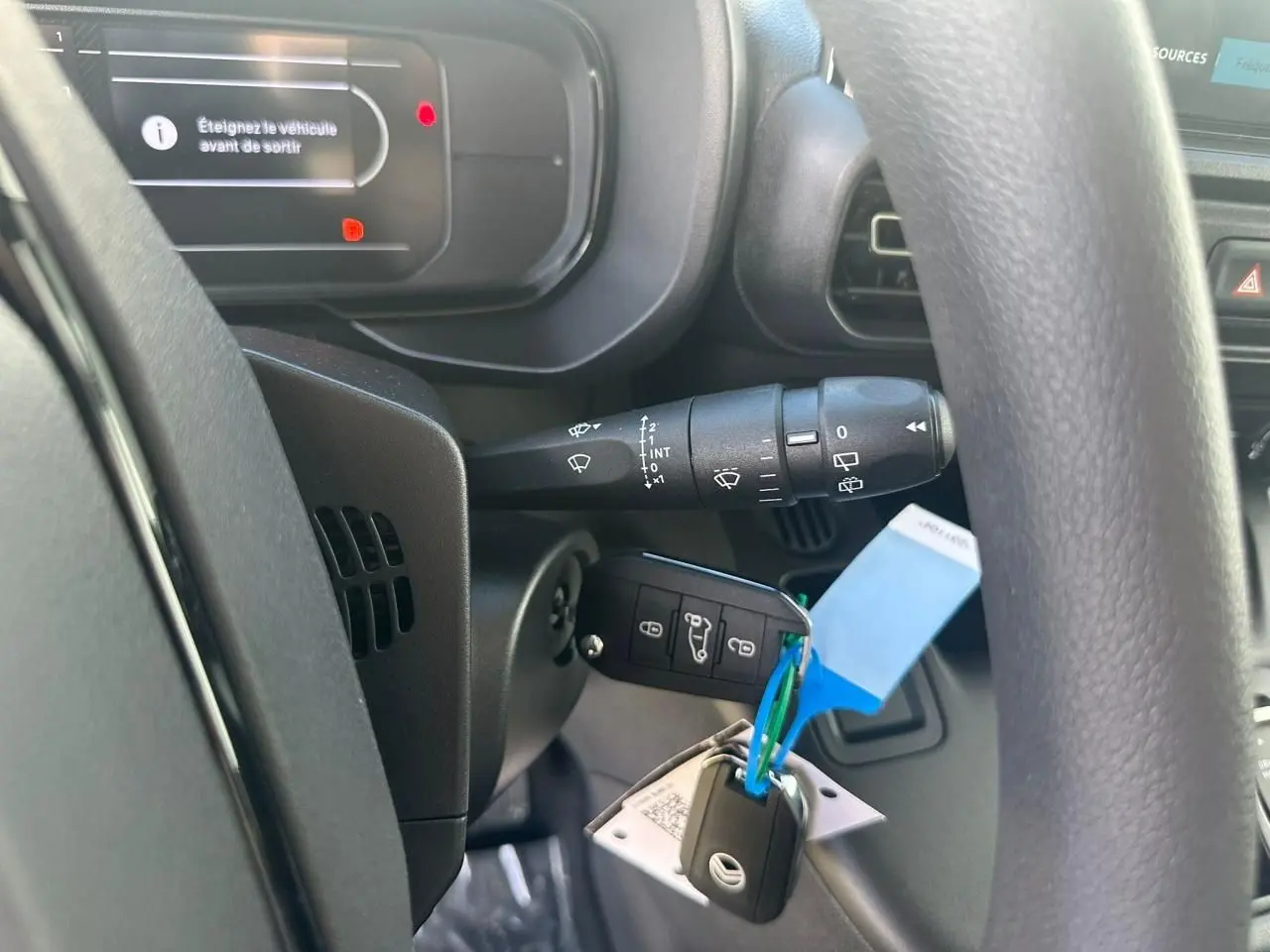 Gros plan intérieur sur le volant et la clé avec plip du Citroën Berlingo blanc, tableau de bord partiellement visible.