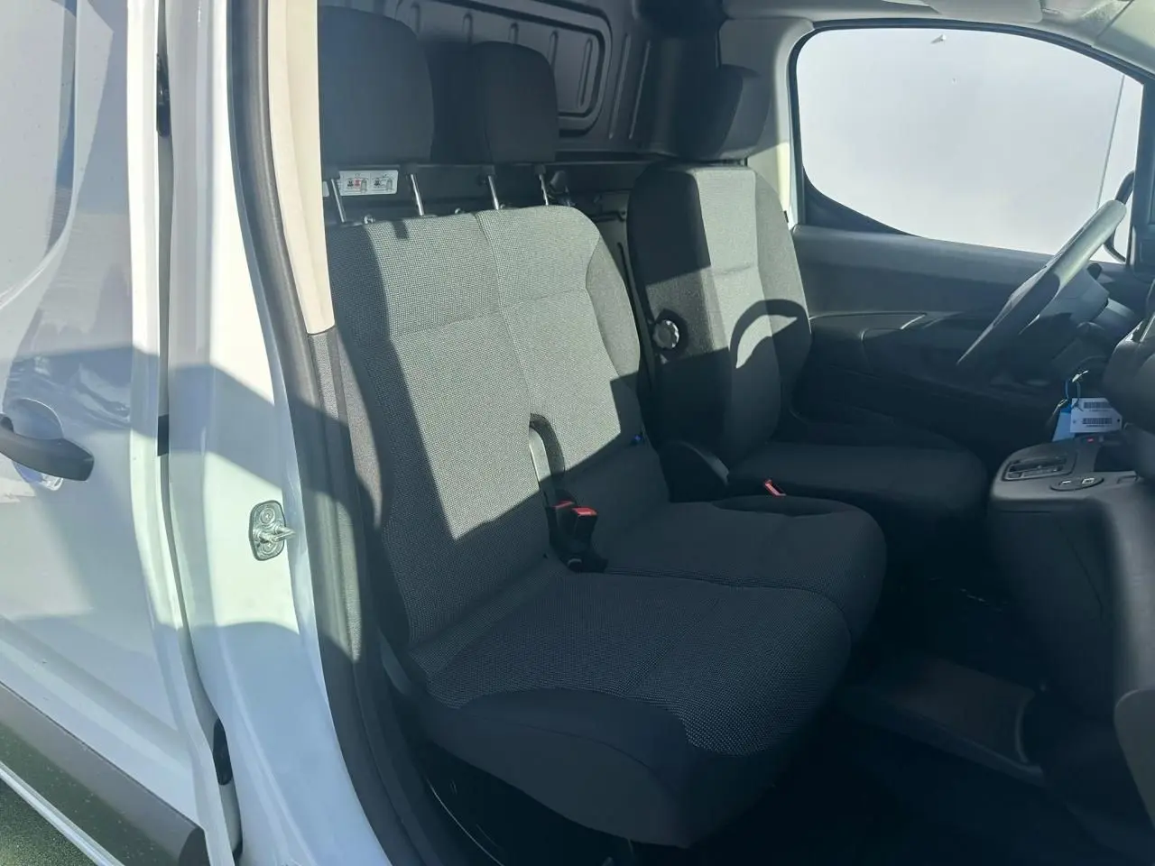 Vue intérieure côté conducteur du Citroën Berlingo blanc Icy, montrant la banquette passager 2 places en tissu gris.