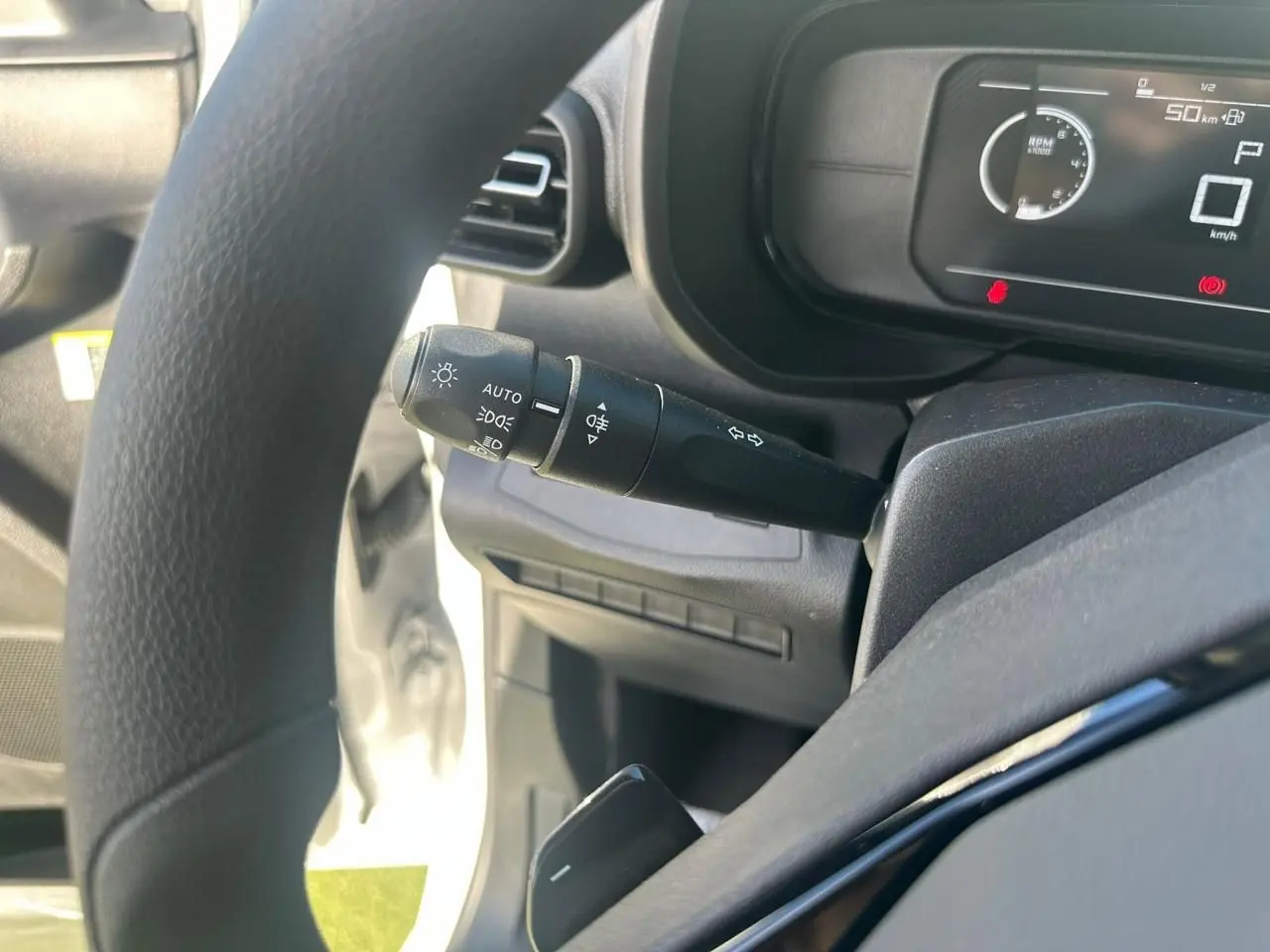 Gros plan sur la commande des feux et clignotants côté gauche du volant d’un Citroën Berlingo blanc Icy 2026.