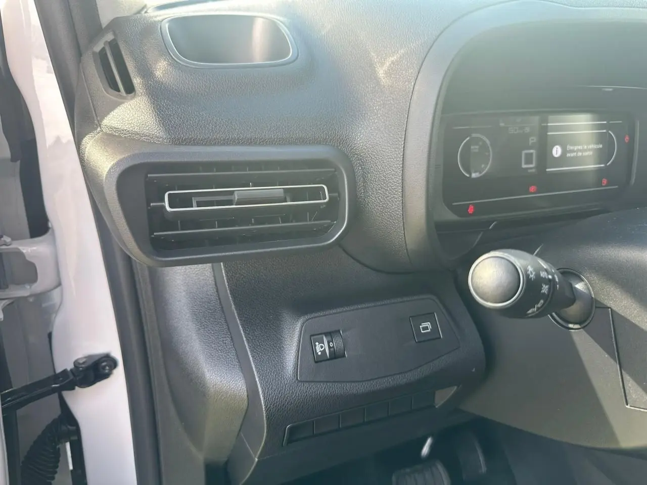 Détail intérieur côté gauche du tableau de bord du Citroën Berlingo blanc, avec aérateur et commandes lumineuses.