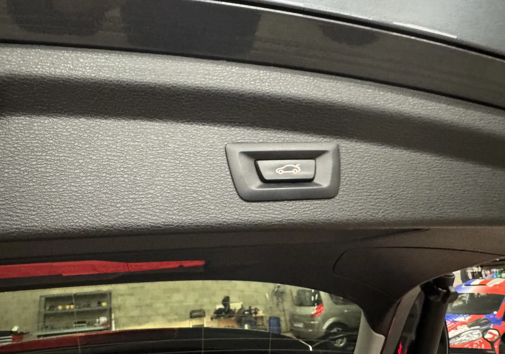 Bouton d'ouverture électrique du hayon vu de l'intérieur du coffre d'un BMW X2 gris Minéral Métallique.