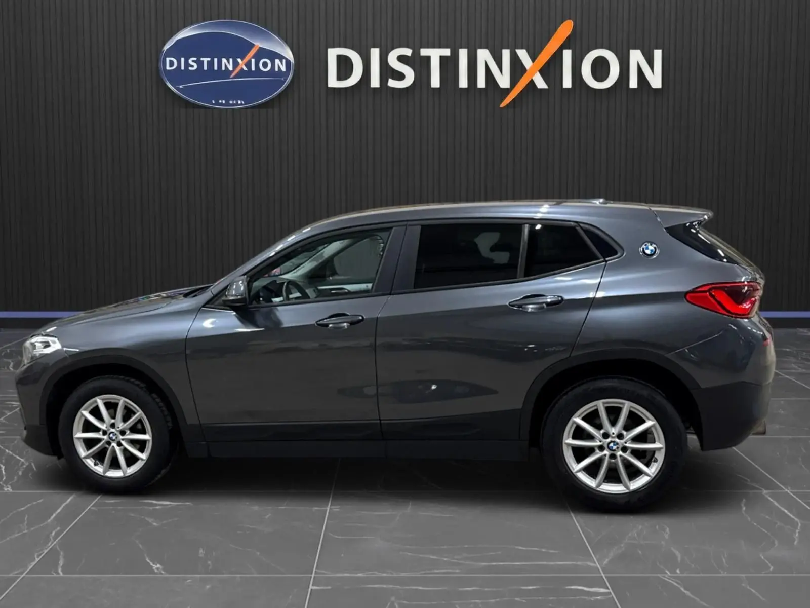 BMW X2 gris minéral métallisé vue de profil côté gauche, vitres arrière surteintées et jantes alliage visibles.