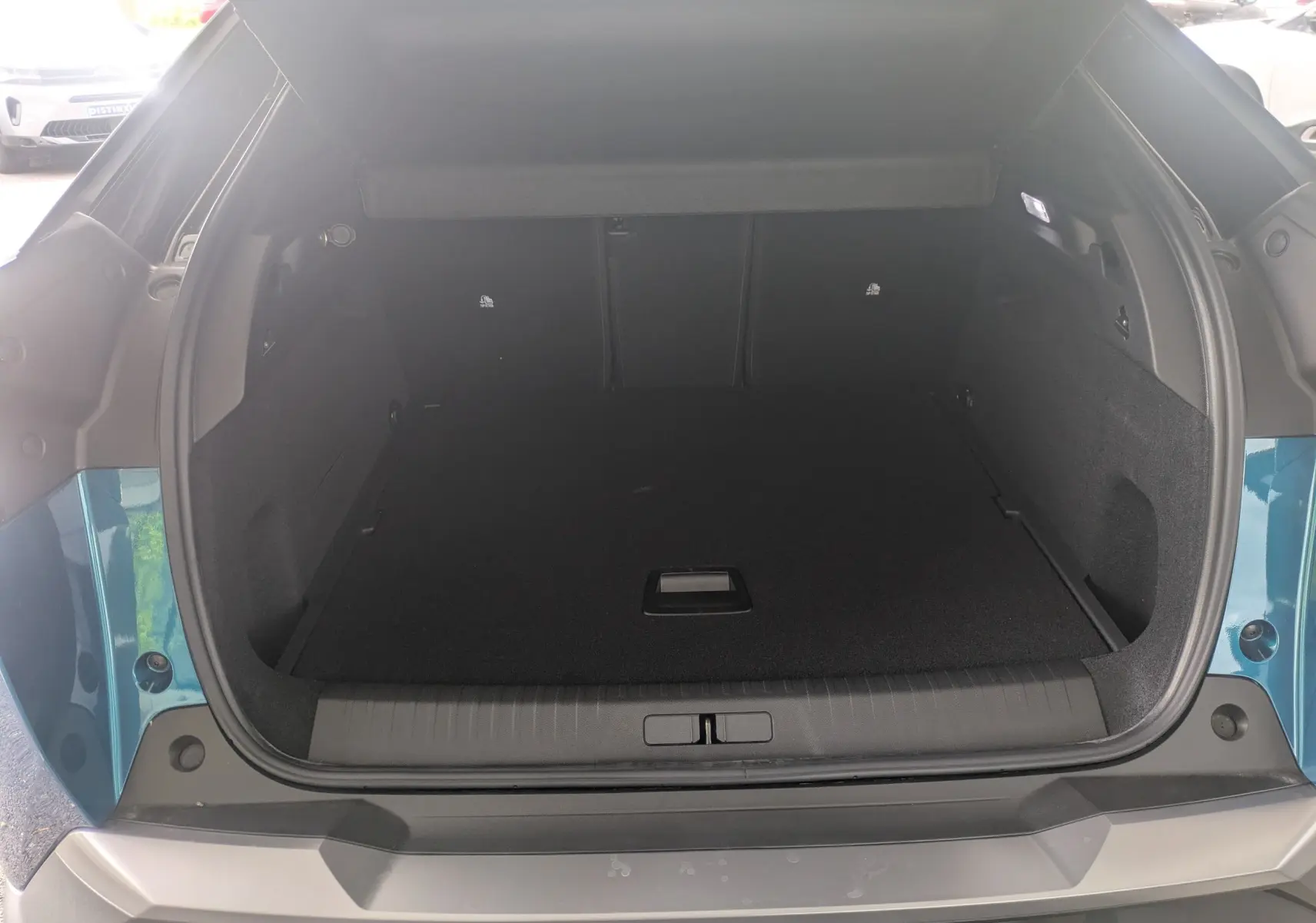 Coffre ouvert vu de l'arrière d'un Peugeot 3008 hybride bleu Obsession avec intérieur noir.