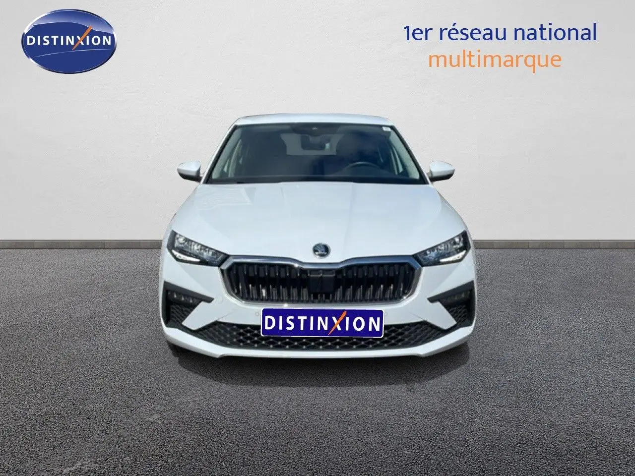 Vue frontale d'une Skoda Scala blanc glacier avec calandre noire et phares LED allumés sur fond neutre.