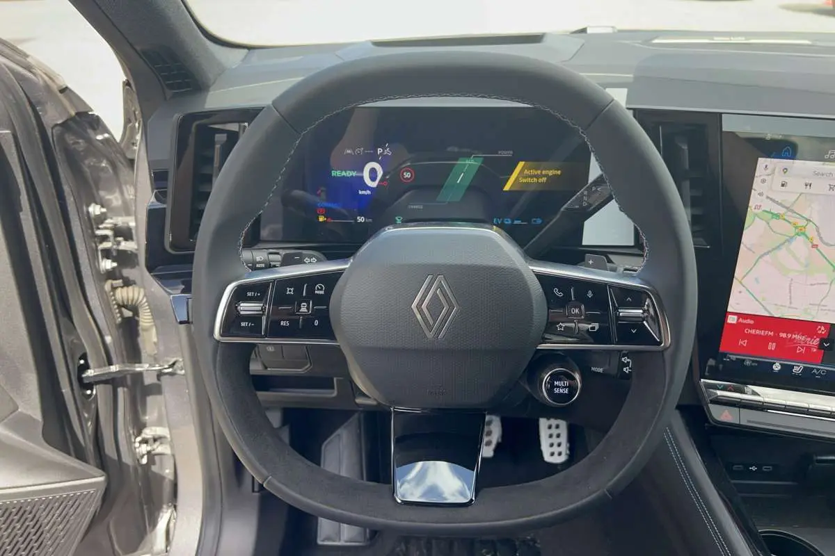 Vue intérieure centrée sur le volant cuir multifonctions du Renault Austral gris schiste avec tableau de bord numérique et écran tactile.