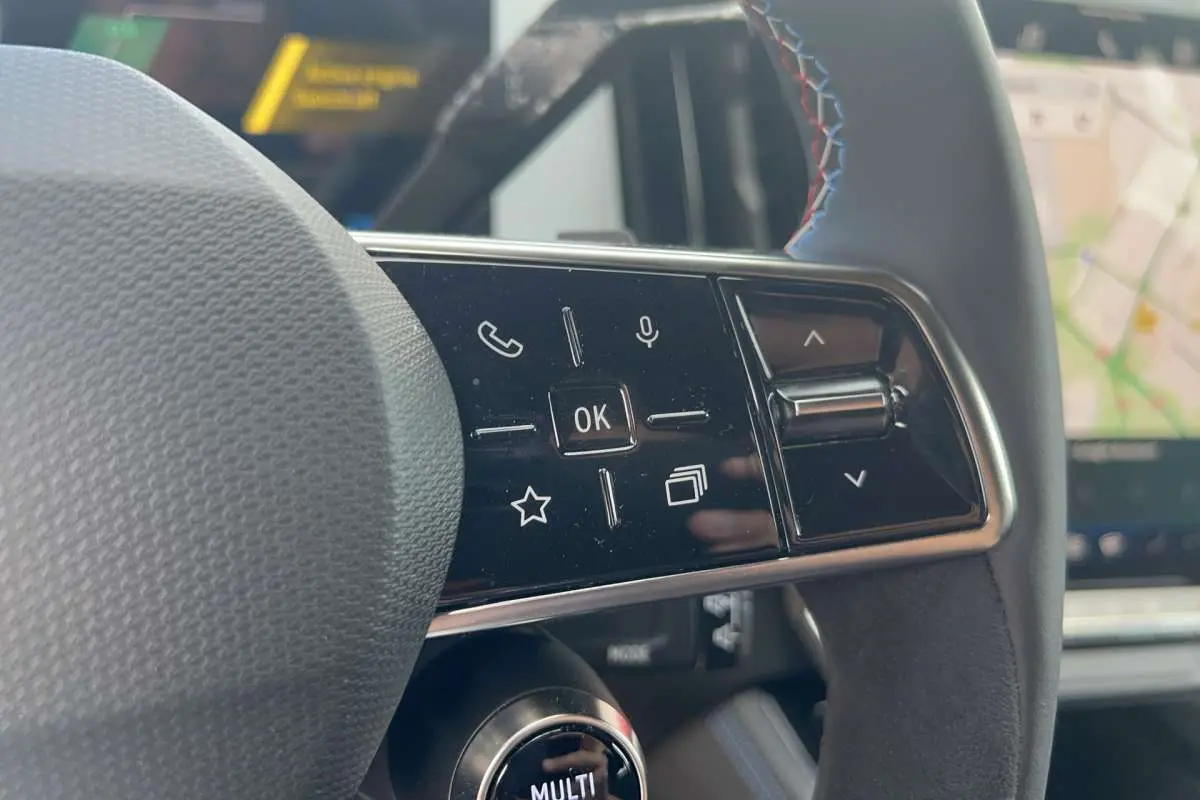 Gros plan sur les commandes multifonctions à droite du volant cuir du Renault Austral 200 Esprit Alpine, avec écran GPS en arrière-plan.