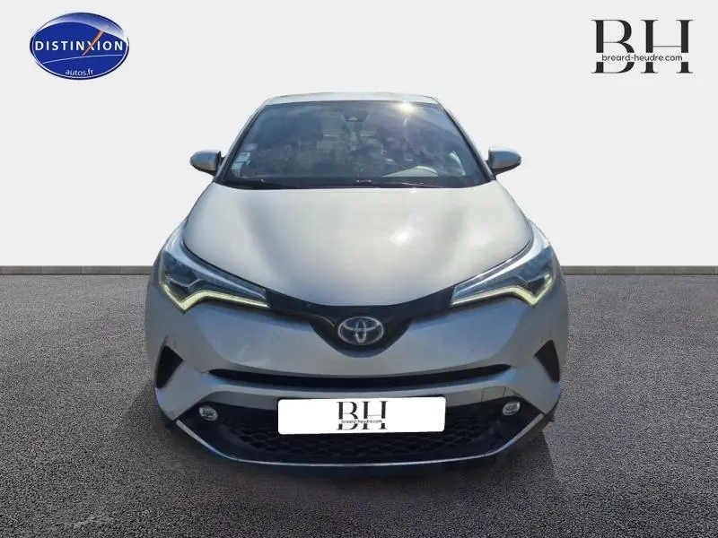 Vue avant d'un Toyota C-HR gris aluminium 2019 avec phares LED en forme de flèche et calandre noire distinctive.