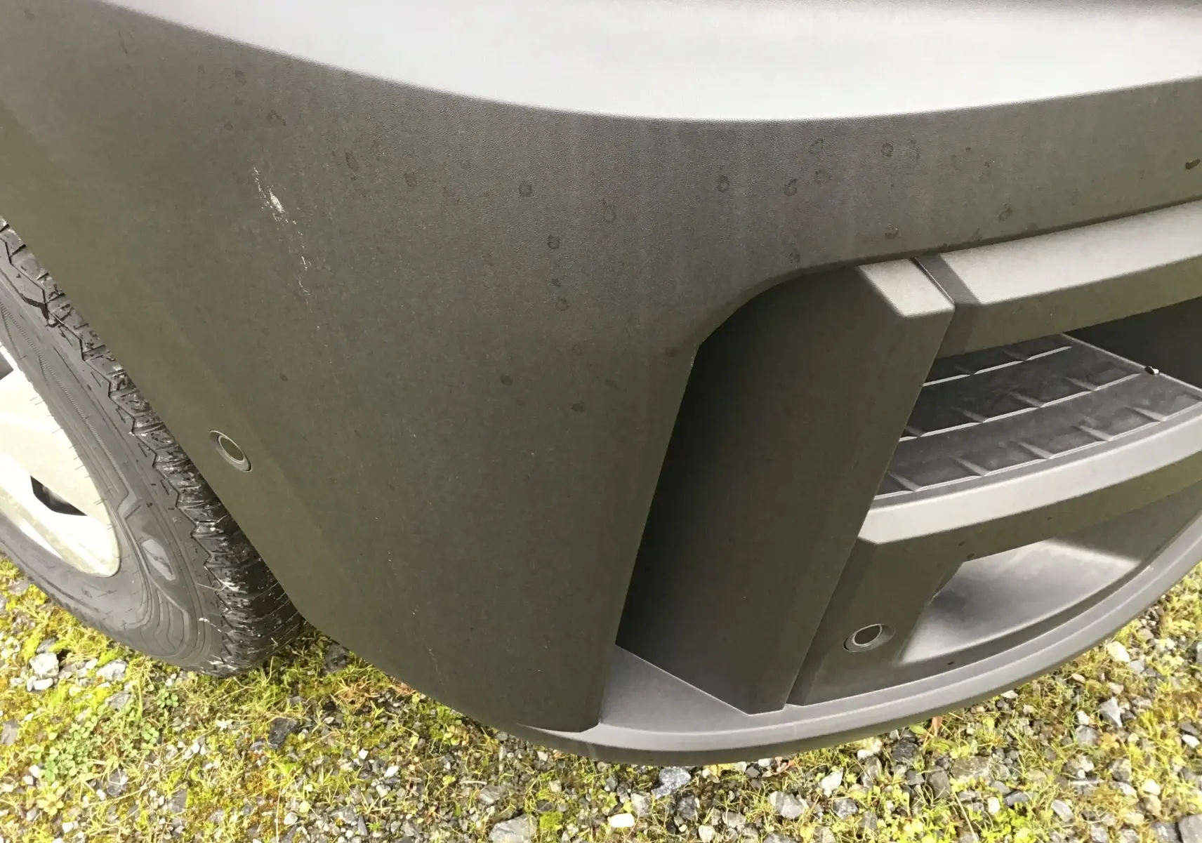 Gros plan sur l'angle avant gauche du pare-chocs gris urbain du Renault Master L2H2 2025 avec capteurs de stationnement.