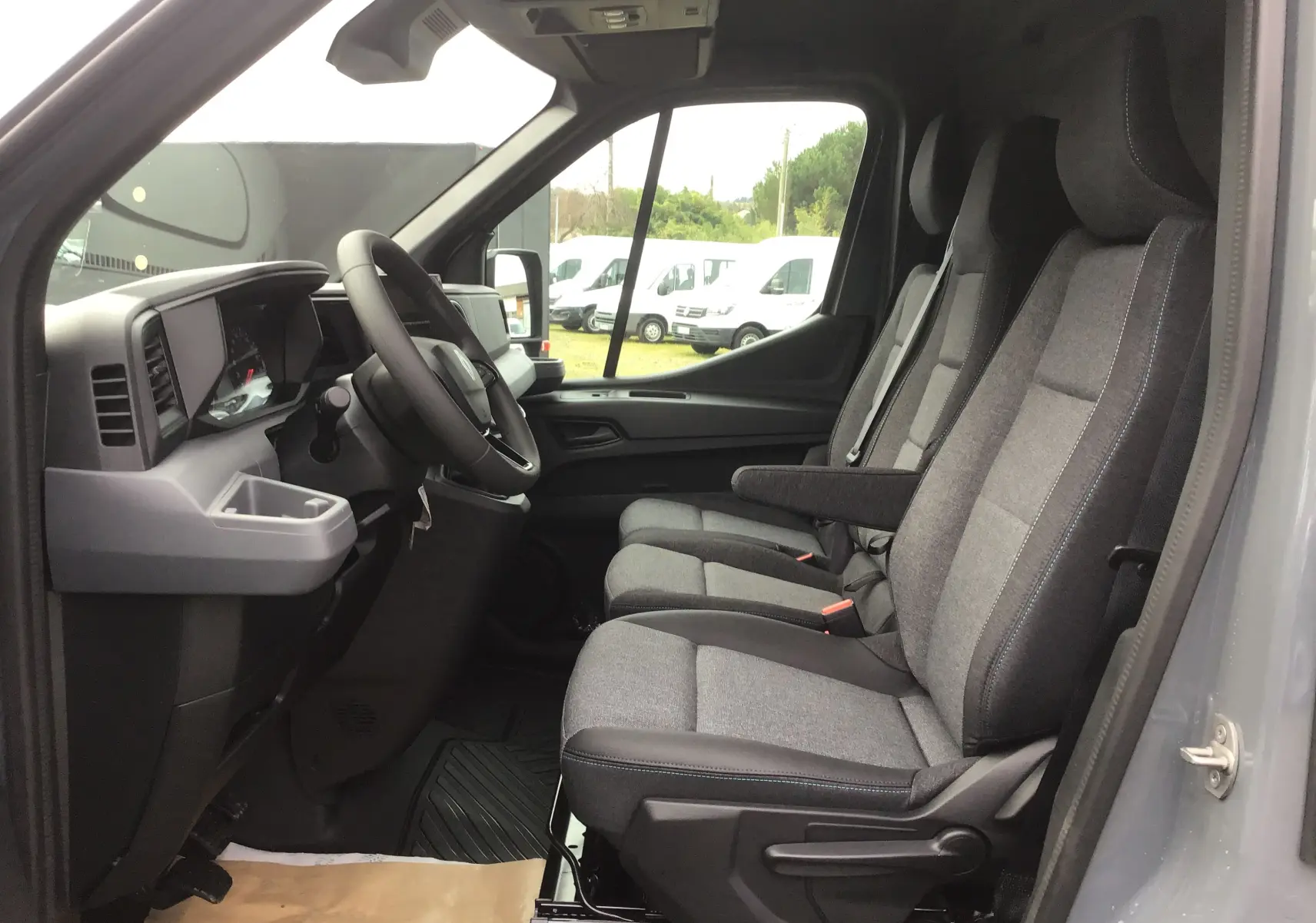Vue intérieure côté conducteur du Renault Master gris urbain 2025, montrant les sièges tissu gris et tableau de bord moderne.