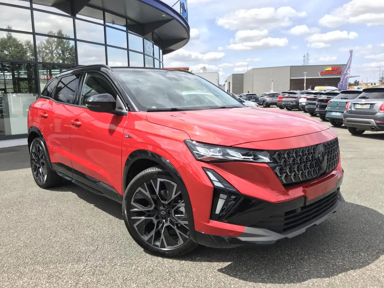 Renault Austral Esprit Alpine rouge et noir, vue 3/4 avant droit, jantes alliage noires et calandre noire distinctive.