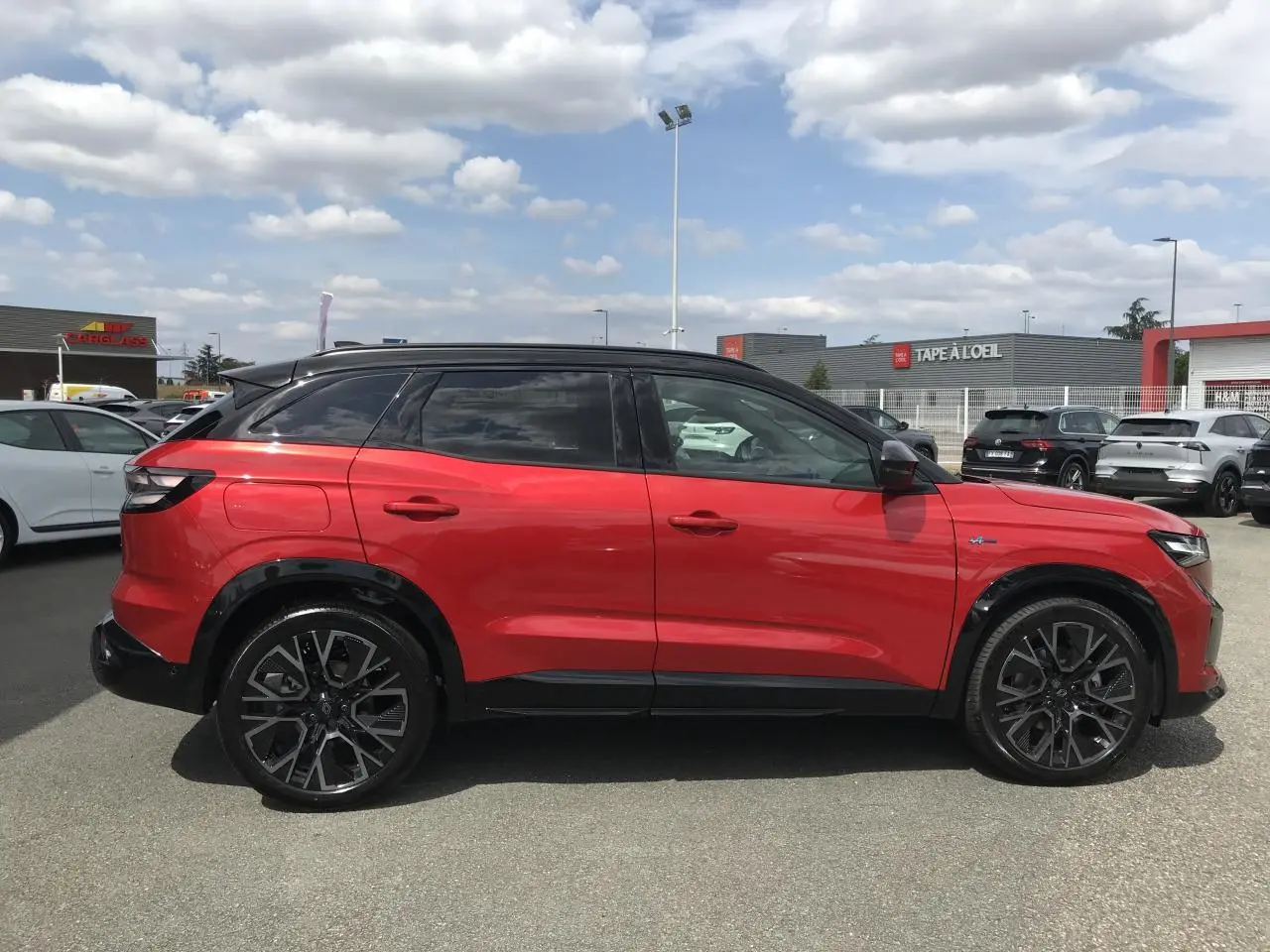 Profil droit du Renault Austral 2025 bi-ton rouge et noir avec jantes alliage noires et toit noir brillant.