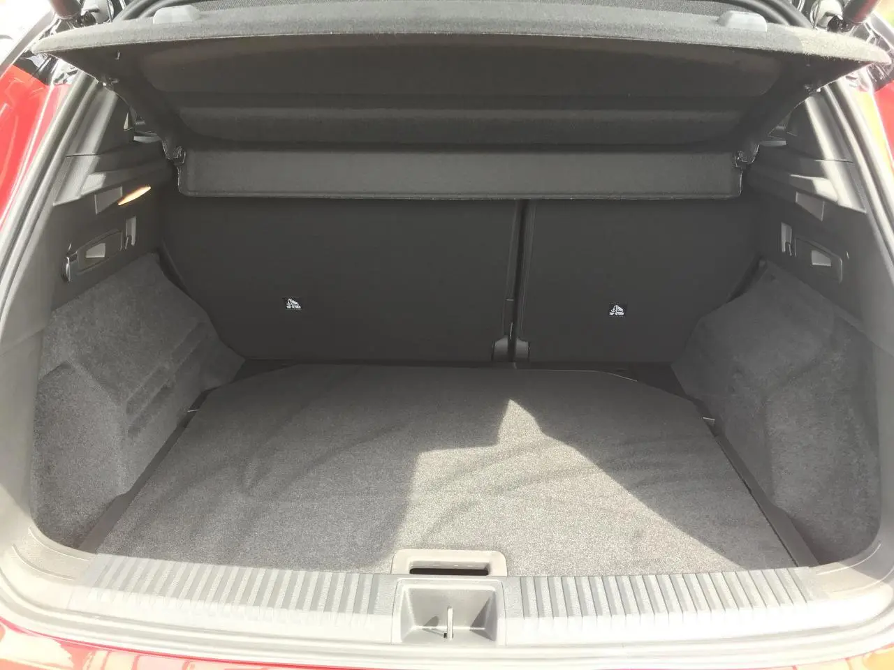 Coffre ouvert vu de l'arrière d'un Renault Austral 2025 rouge et noir, montrant un espace de chargement propre et spacieux.