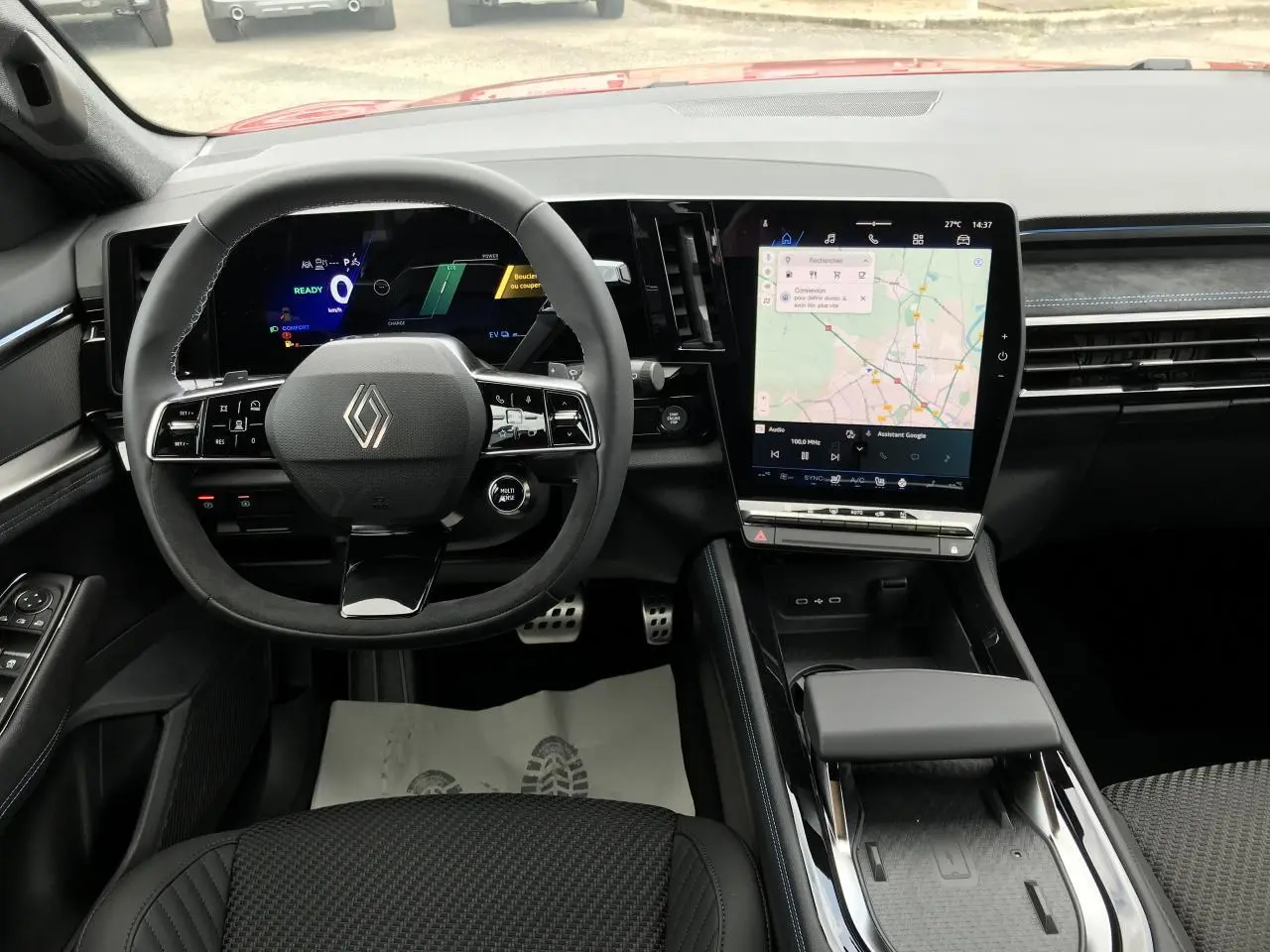 Vue intérieure avant du tableau de bord du Renault Austral rouge noir, avec écran tactile vertical et volant multifonction.