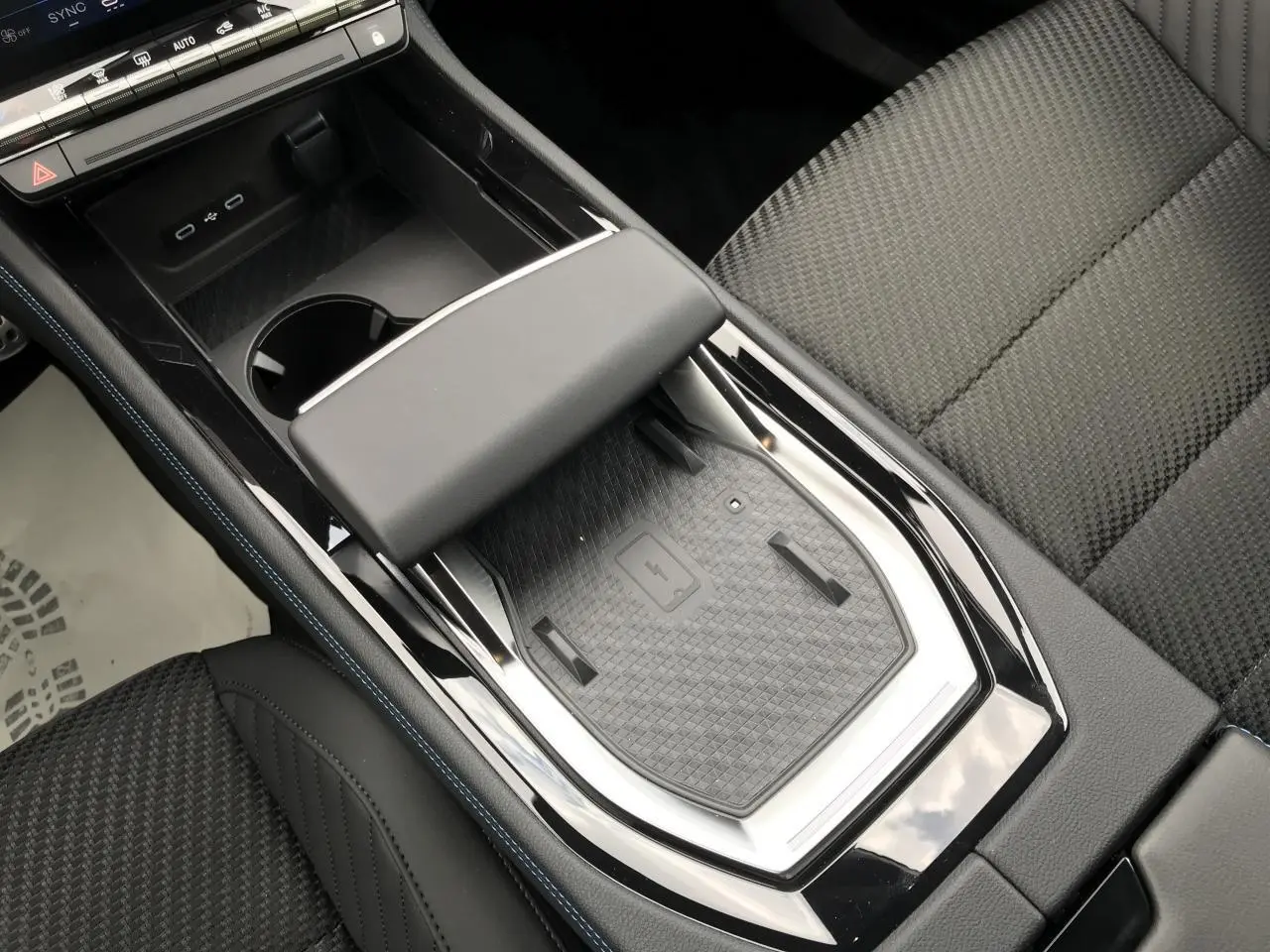 Vue plongeante sur la console centrale noire du Renault Austral 2025 avec chargeur sans fil et accoudoir cuir.