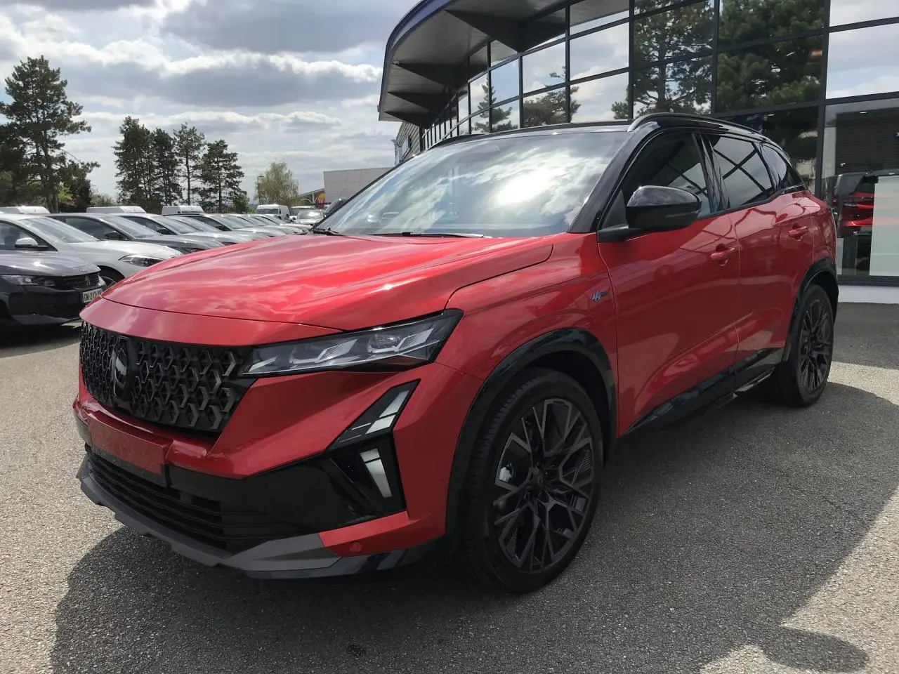 Renault Austral full hybrid rouge et noir en 3/4 avant droit, avec jantes noires et toit bi-ton métallisé.