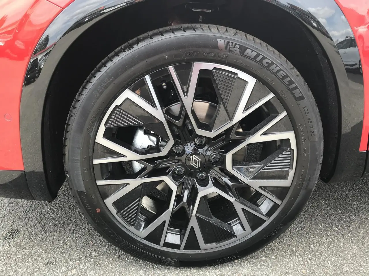 Gros plan sur la jante alliage 20 pouces noir et argent du Renault Austral rouge et noir, côté avant droit.