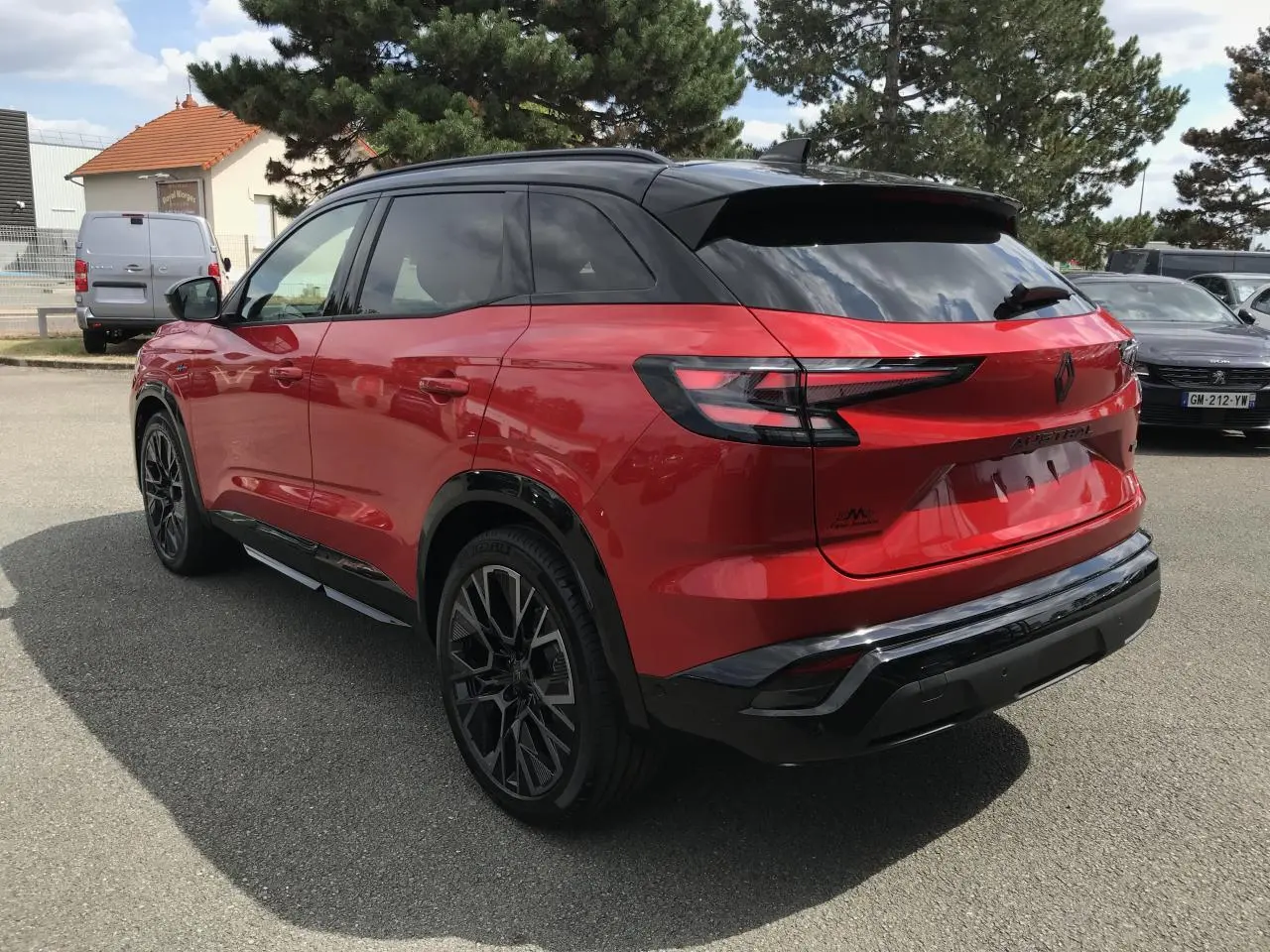 Renault Austral full hybrid rouge et noir en 3/4 arrière droit, jantes alliage noires et toit noir brillant.