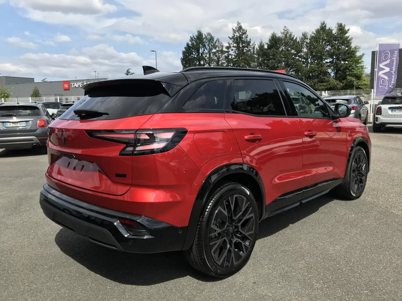 Vue 3/4 arrière droite du Renault Austral rouge et noir avec jantes alliage noires et toit noir métallisé.