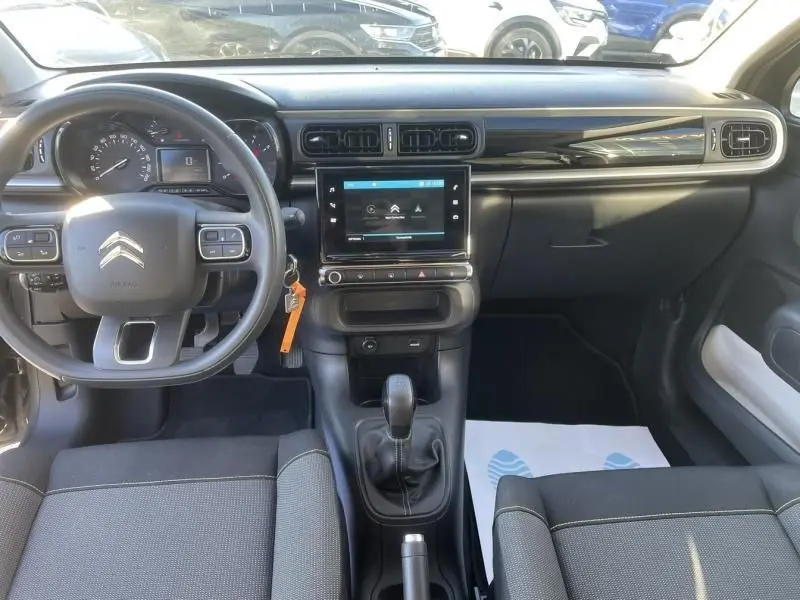 Vue intérieure avant de la Citroën C3 2021 gris foncé, avec tableau de bord moderne et boîte manuelle au centre.
