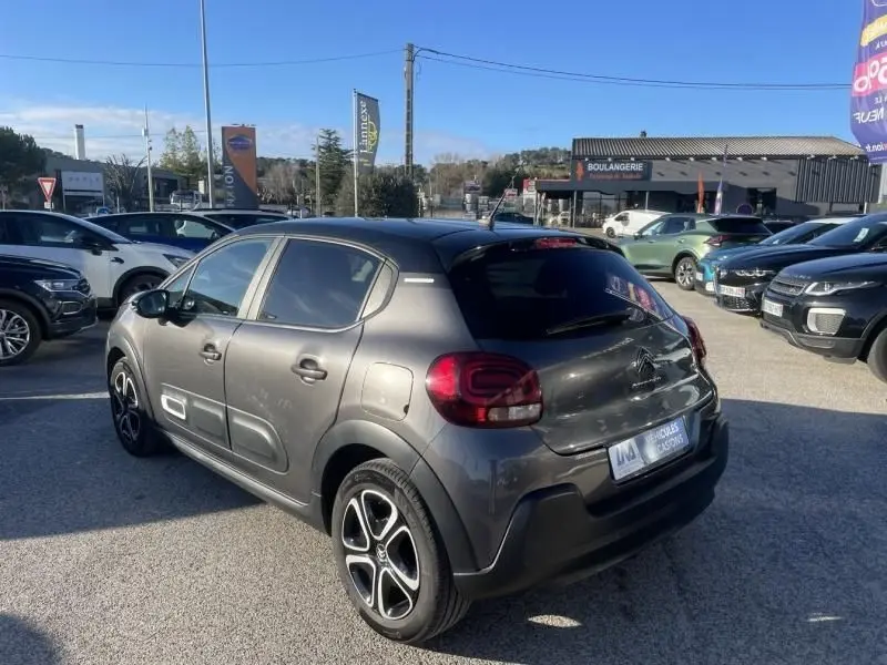 Vue 3/4 arrière droite d'une Citroën C3 gris foncé 2021 avec jantes distinctives et protections latérales blanches.