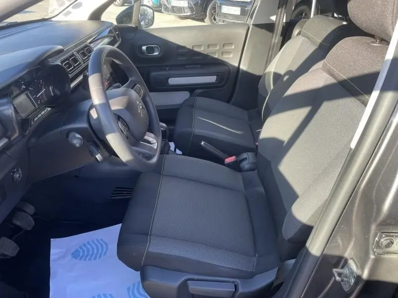 Vue intérieure côté conducteur de la Citroën C3 gris foncé 2021, montrant sièges tissu et tableau de bord épuré.