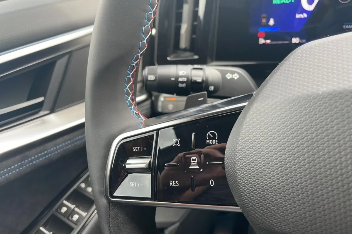 Gros plan sur le volant cuir multifonctions avec surpiqûres bleues du Renault Austral New 200 Esprit Alpine, intérieur gris.