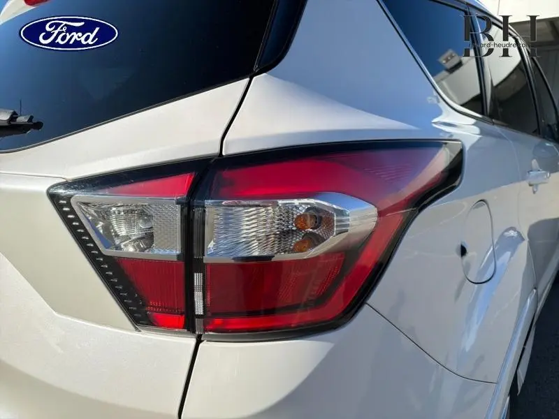 Gros plan sur le feu arrière droit d’un Ford Kuga blanc Premium Platinum, mettant en valeur les lignes du coffre et la portière.